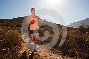 Blonde female trail runner running through a mountain landscape