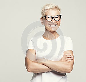 blonde fifty year old European female with stylish pixie haircut and eyeglasses smiling at camera