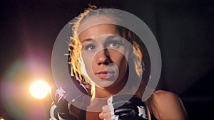 A blonde fighter in macro view raises her fists. Woman fighter portrait. HD.
