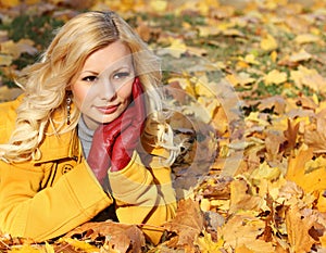 Blonde girl in Autumn Park with Maple leaves. Fashion
