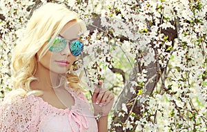 Blonde Girl with Aviator Sunglasses over Cherry Blossom. Spring