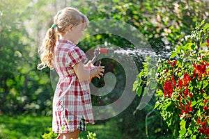 A blonde girl baby walks on a sunny day, takes care of the garden
