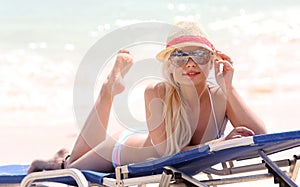 Blonde girl on the beach with summer hat and sunglasses