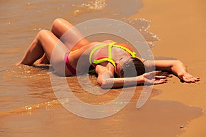 blonde girl in bikini upside view lies on back on wet sand