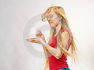 Blonde girl blowing hair holds coffee cup