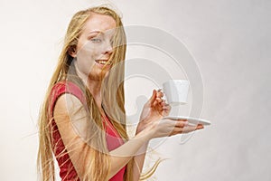 Blonde girl blowing hair holds coffee cup