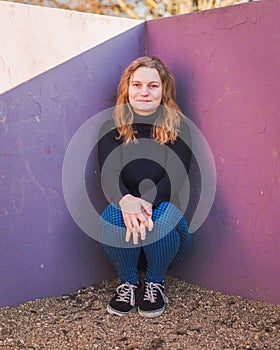 Blonde girl with blue eyes with tyrian purple wall as background in a park in a winter sunny day