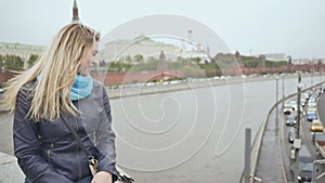 A blonde girl from the bridge sends an air kiss to motorists against the backdrop of the Kremlin. Moscow. Russia