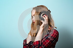 Blonde girl in a checkered shirt with headphones.