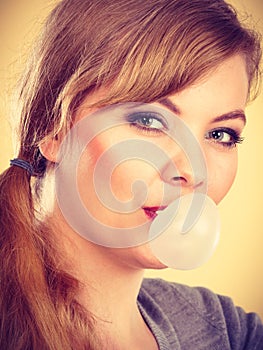 Blonde girl chewing gum making balloon.