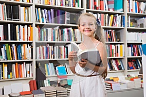 Blonde girl chooses a book in the library