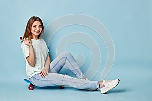 Blonde girl with chupa chups sitting on a skateboard photo