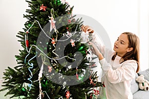 Blonde girl decorating christmas tree at home