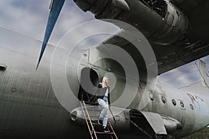 A blonde girl descends the ramp from an old decommissioned Soviet military cargo plane An-12