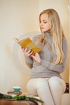 Blonde girl drinking her coffee, eat cookies and read a book