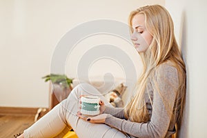 Blonde girl drinking her coffee, eat cookies and read a book