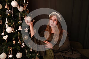 Blonde girl in an elegant long green dress celebrates Christmas