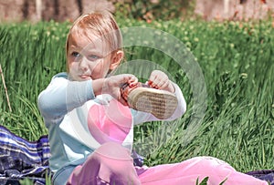 Blonde, a girl of five years old sits in the garden on the grass