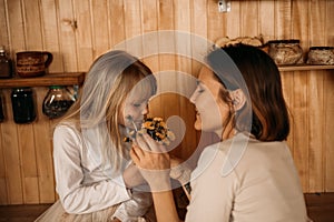 Blonde girl gives mom flowers for mother`s day. Mom and daughter are considering a bouquet of dandelions