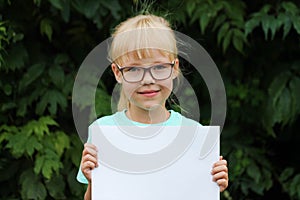 Blonde girl with glasses holding a blank sheet of paper with space for text