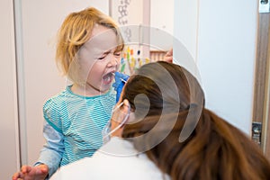 Blonde girl having oropharyngeal swab inserted for covid 19 detection.