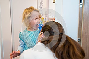 Blonde girl having oropharyngeal swab inserted for covid 19 detection.