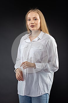 Blonde girl in jeans and white shirt over black background