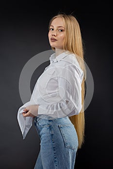 Blonde girl in jeans and white shirt over black background