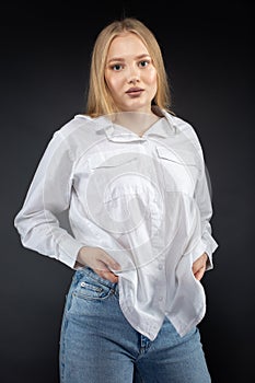 Blonde girl in jeans and white shirt over black background