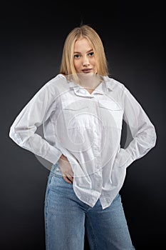 Blonde girl in jeans and white shirt over black background