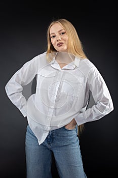 Blonde girl in jeans and white shirt over black background