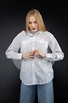 Blonde girl in jeans and white shirt over black background