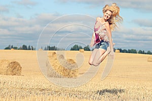 Blonde girl jumps in sloping field