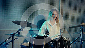 Blonde girl is learning to play drums, cymbals