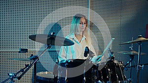 Blonde girl is learning to play drums, cymbals