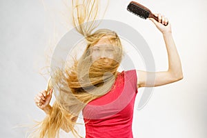 Blonde girl long blowing hair holds two brushes