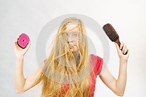 Blonde girl long blowing hair holds two brushes
