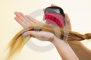 Blonde girl with long braid hair holds brush