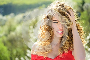 Blonde girl with long and curly wavy hair. Beautiful model with curly hairstyle. Fashion haircut. Beautiful attractive