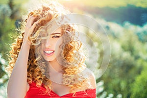 Blonde girl with long and curly wavy hair. Beautiful model with curly hairstyle. Fashion haircut. Beautiful attractive