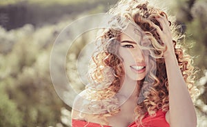 Blonde girl with long and curly wavy hair. Beautiful model with curly hairstyle. Fashion haircut. Beautiful attractive