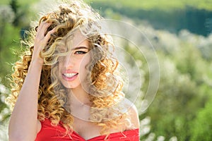 Blonde girl with long and curly wavy hair. Beautiful model with curly hairstyle. Fashion haircut. Beautiful attractive