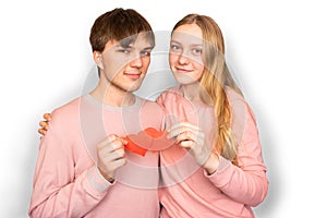 Blonde girl with long hair and brown-haired guy are holding two red hearts in their hands, symbol of love. White background