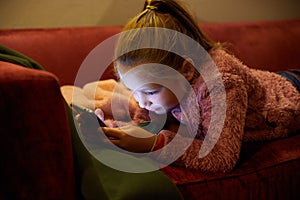 Blonde girl lying on sofa watching smartphone