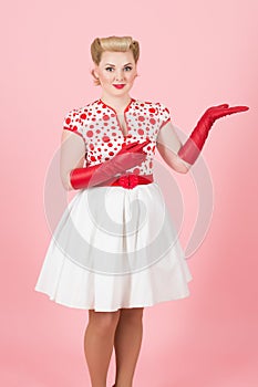 Blonde girl make advertising by hand in red gloves. Beautiful woman demonstrate place on hand. Pretty lady sales on pink