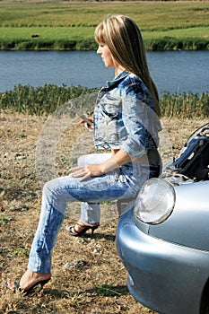 Blonde girl-mechanic sitting on the car