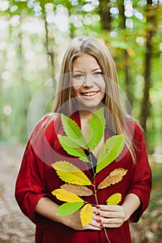 Blonde girl in a misterious forest holding a branch