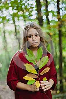 Blonde girl in a misterious forest holding a branch