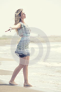 Blonde girl opening arms outstretched toward the sea