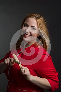 A blonde girl with an overweight plus size, in a red overallposing on a dark Studio background